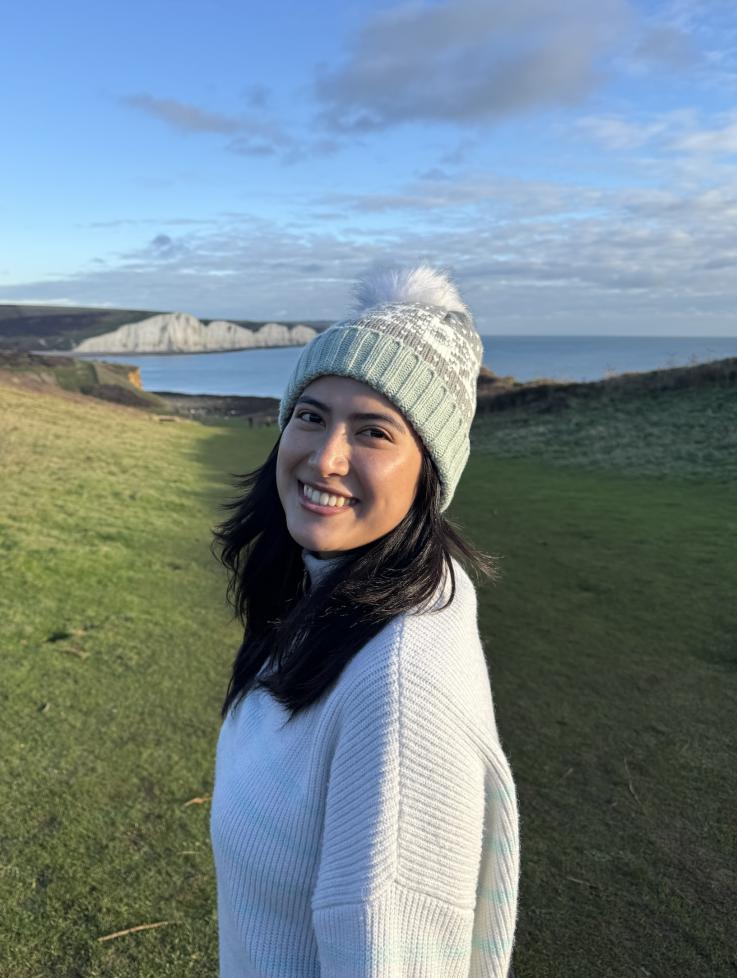 Pathobiology student Prerana Shrestha wears a winter hat and smiles at the camera with the ocean in the backgroun