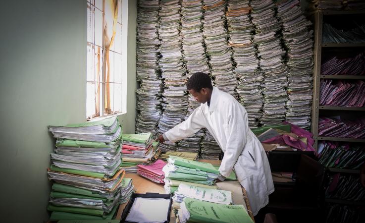 Mercy Wanjiku, lab technologist, reviews paper medical records in the UW Treatment, Research, and Expert Education (TREE) laboratory at Coptic Hospital in Nairobi, Kenya. Photo of medical facility in Kenya
